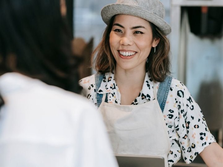 A young woman in an apron serving at a counter