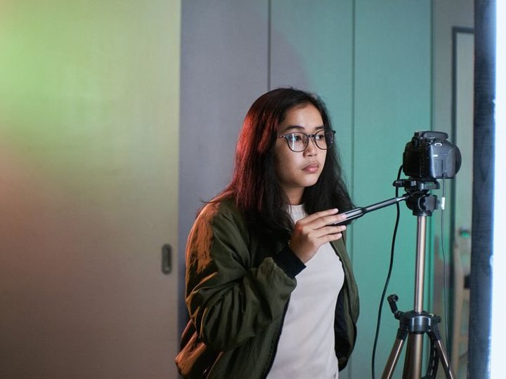 A young woman working a camera on a tripod